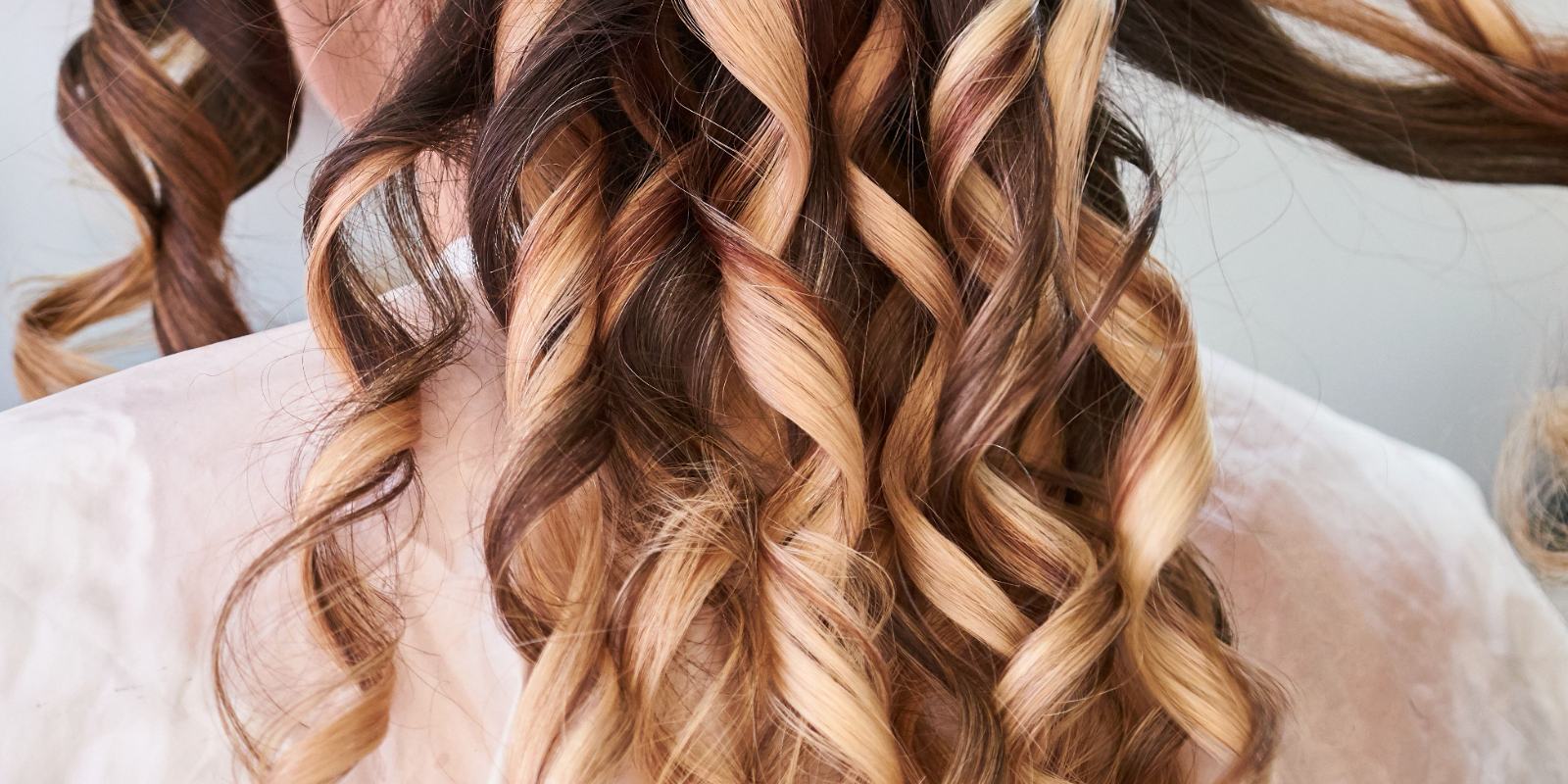 Licensed stock photograph: long hair set in loose curls, blonde through brown, falling over a styling cape.